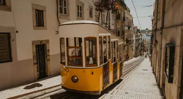 A yellow tram on a steep cobbled street in Lisbon